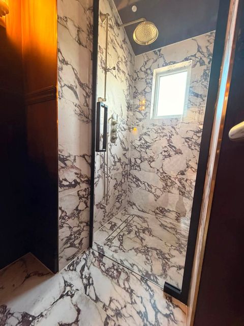 Wet room shower seen from the bathroom doorway, marble-effect tiling and frameless glass
