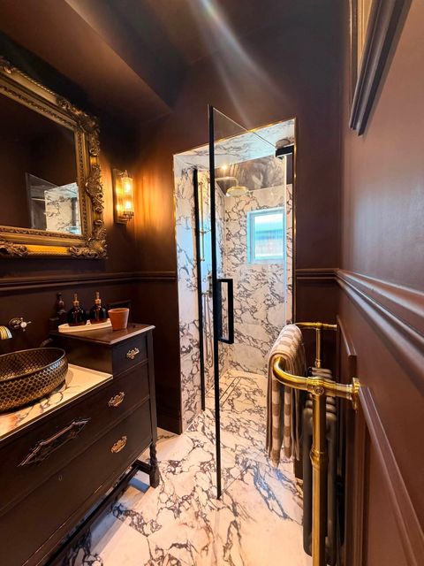 Brass rain head and slide-rail shower on marble-effect tiling