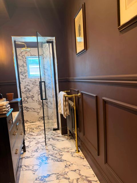 Cast iron column radiator on a brass towel rail against panelled walls